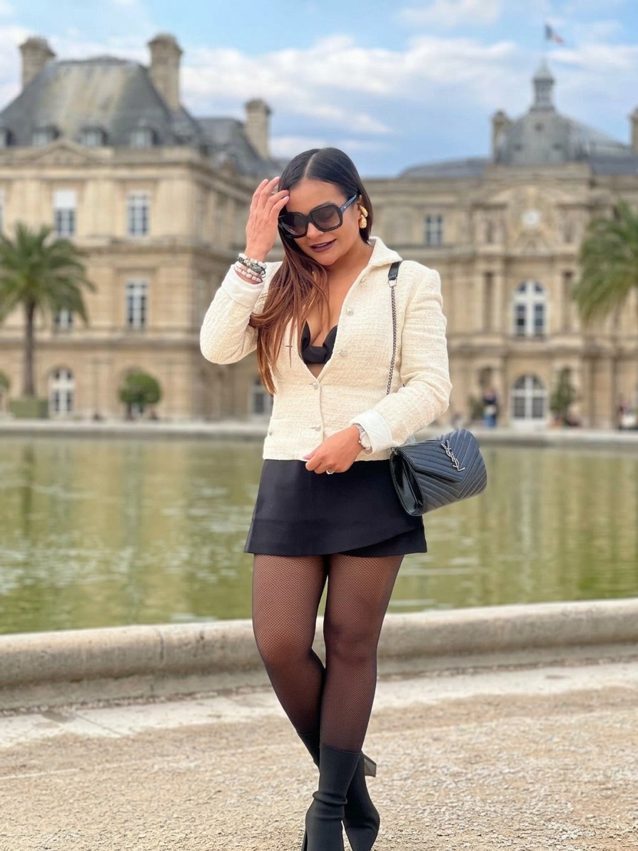 Stephanie Noguera con chaqueta blanca y falda negra en un jardín de París